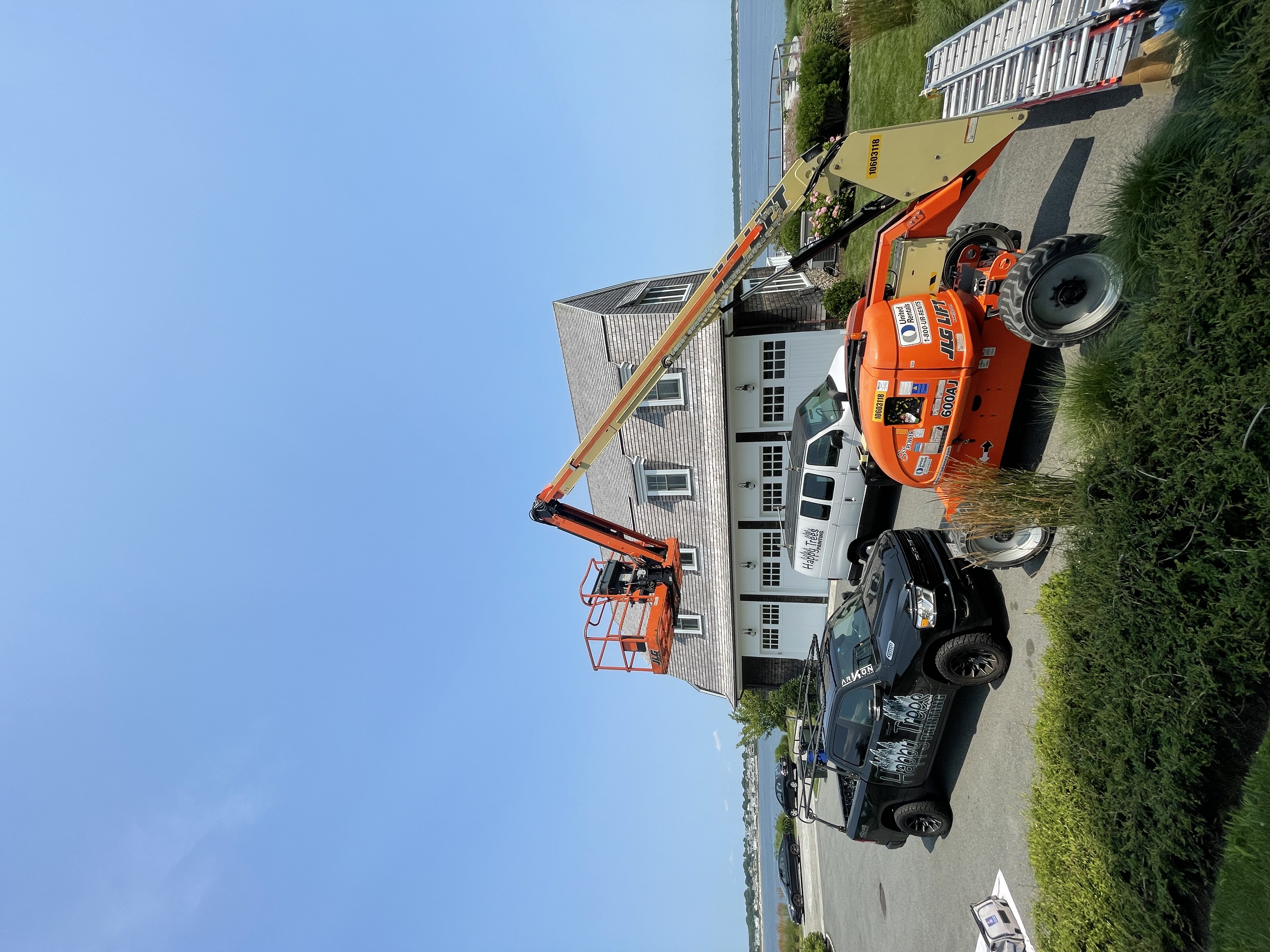 Large residential exterior painting job with lift equipment in coastal Rhode Island